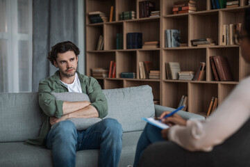 Unhappy millennial european male listen black lady psychologist in modern clinic interior