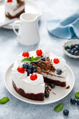 Chocolate cake, white cheesecake decorated with blueberries, cherry, brown chocolate and whipped cream