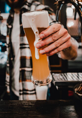Fototapeta na wymiar bartender hand holding glass with beer in a bar or pub