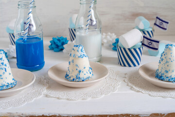 Israeli dessert Krembo (chocolate covered marshmallow cookie) for Independence Day on holiday table with party food and drinks in national colors.