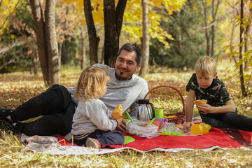 Father with children have a picnic in autumn park. Weekend. family pastime