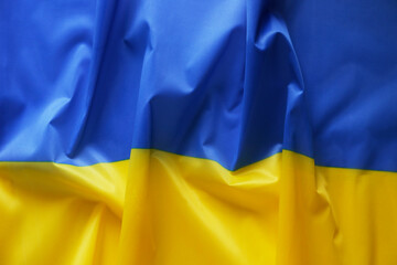 Close up shot of ruffled Ukrainian yellow and blue flag with a lot of copy space for text. Textured background.
