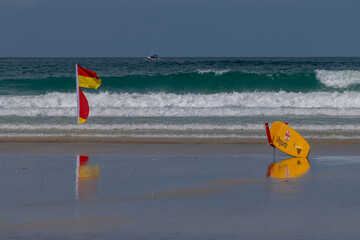 Lifeguard paddleboard and red and yellow warning flag