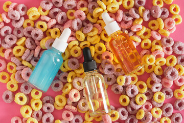 serum in a mock-up dropper glass bottle on the background of multi-colored breakfast cereals, creative advertising