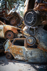 Fototapeta na wymiar A lot of rusty burnt cars in Irpen, after being shot by the Russian military. Russia's war against Ukraine. Cemetery of destroyed cars of civilians who tried to evacuate from the war zone
