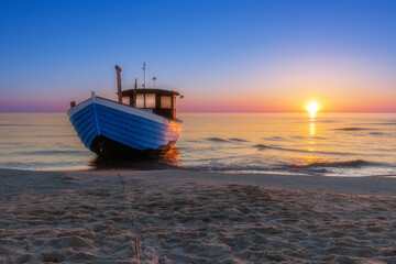 Blauer Fischkutter am Strand der Ostsee auf der Insel Usedom zum Sonnenaufgang