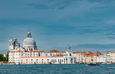Fototapeta na wymiar Panoramic view over Grand Canal with Basilica di Santa Maria della Salute, in Venice historical downtown, Italy, at sunny warm day and blue sky.