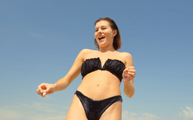 Bottom view of a wet woman in a black swimsuit. Portrait of a woman under the shower