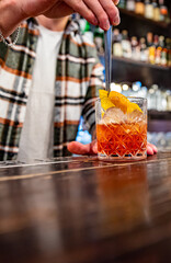 man bartender hand making negroni cocktail. Negroni classic cocktail and gin short drink with sweet vermouth, red bitter liqueur