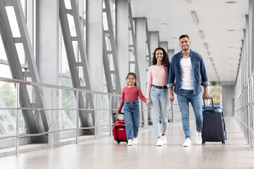 Travel Insurance. Smiling Arabic Family With Daughter Walking With Suitcases At Airport