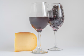 Smoked Gouda cheese, glass of wine, on white background with copy space.