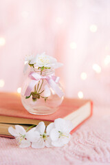 Open old book with white small flowers on a pink background	