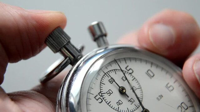 Old Stopwatch mechanism in man's hand. Man push start button or holding stopwatch.