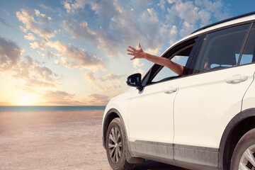 Fototapeta na wymiar Toward adventure! Guy relaxing and enjoying road trip. Happy man rides into the sunset in car.