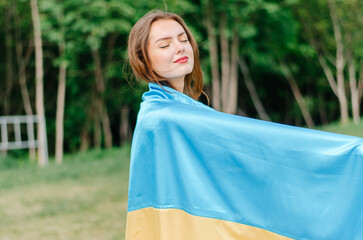 Ukrainian woman with the flag of Ukraine. Girl with the flag of Ukraine. Flag of Ukraine. Ukraine. Patriotic photo of a girl with a blue and yellow flag of Ukraine