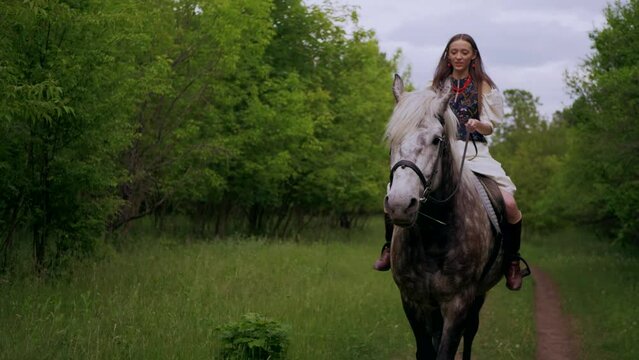Woman riding a horse. Girl in an embroidered shirt with a horse on a walk. Ukraine
