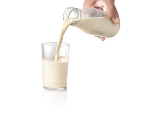 Milk pouring into the clear glass isolated on white background
