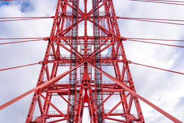 Close-up of fragment of red cable-stayed bridge pylon in place where metal cables are fastened....