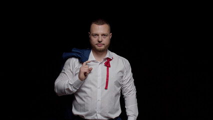 A sexy man in a white shirt and an unbuttoned red tie looks ahead brazenly