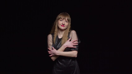 A young seductive woman in a dark dress poses on a black background, fashion and glamour