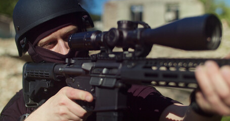 Obraz premium Sniper looks into the optical sight and fires a shot.