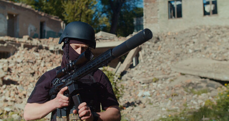 A soldier against the background of a destroyed building comes up with a magazine with cartridges for a rifle