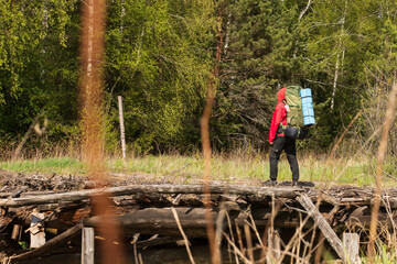 A tourist, a traveler with a backpack on his back, walks along a dilapidated bridge, a crossing.