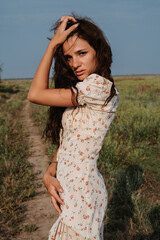 A young Caucasian woman posing standing on a path in a picturesque steppe boundless landscape. Autumn or summer