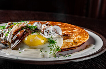 pancake with mushroom sauce, bacon and egg on plate