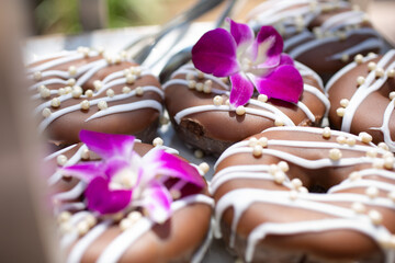 A view of a tray of chocolate donuts with streaks of white frosting.