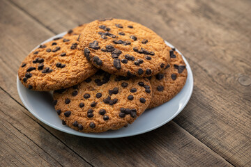 Cookies with chocolate drops on a plate on a wooden table
