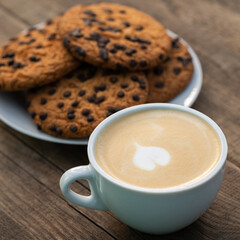 Cappuccino with latte art in the form of a heart and cookies with chocolate drops
