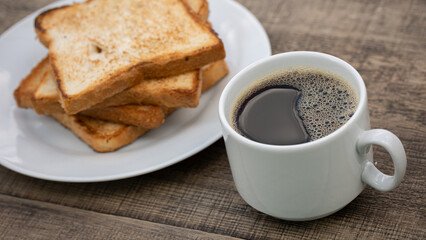 Cup of black coffee and toasted toast on wooden table