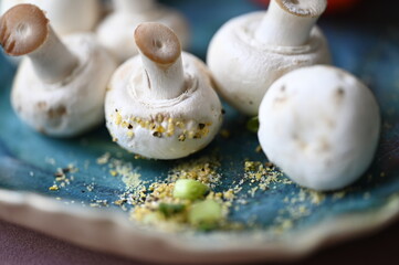 Unwashed mushrooms on a blue plate accompanied by a sliced piece of tomato with juicy seeds -...