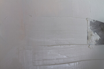 Putty the wall in the house with putty using a spatula to level the surface irregularities