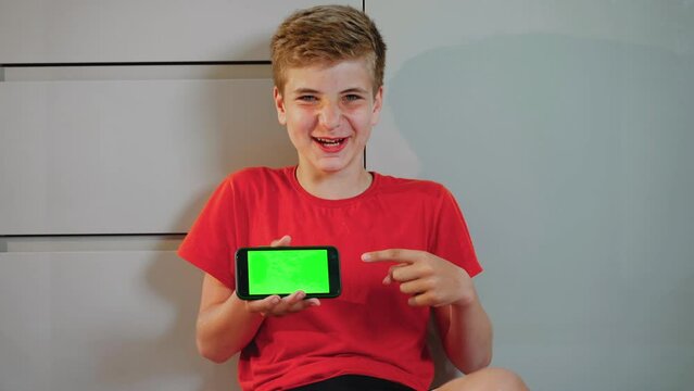 Child holding phone with green background. Guy points finger at touch screen with green screen and shakes head approvingly. Endorsement of game or advertisement that may be displayed on phone
