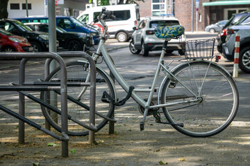 Ein graues Fahrrad steht angeschlossen an einem Fahrradständer in der Stadt
