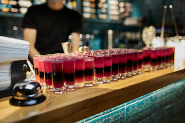 a lot of red alcohol shots on the bar counter, close-up