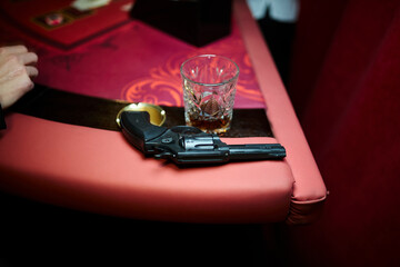 toy gun and glass with alcohol on the table, props for a theme party