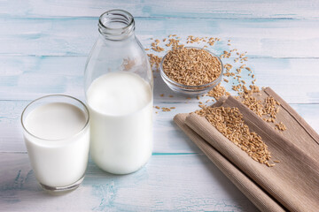 Milk and spelt grain in a bowl on white background.
