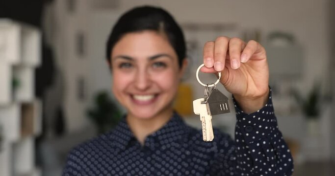 Happy Indian woman holding keys from bought with accumulated funds new house, closeup view hand holding bunch of keys. Female taking bank mortgage, acquire affordable dwelling, first apartment concept