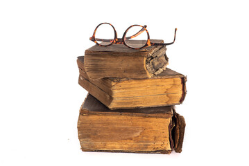 stack of yellowed, vintage books and glasses on white background