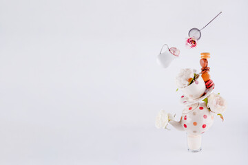 balancing structure of polka dot teapot, cup and saucers with macaroons and levitating milk jug and...