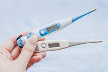 female hand holding electronic baby and adult thermometer. diagnosis of diseases. Types of...