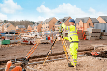 Site engineer in hi-viz installing surveying instrument on construction site