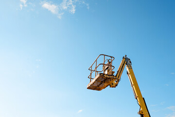 Telescopic boom lift rised up on blue sky background delivered to constraction site ready to be...