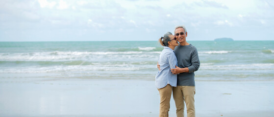  Asian Senior couple  walking on the beach enjoy life  at sunrise