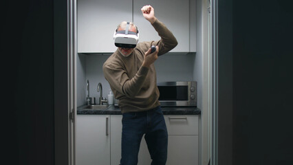 Happy aged man in augmented reality headset dancing in small kitchen