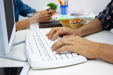 Close-up the hand typing on the keyboard while working on the computer in the office.