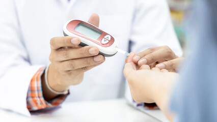 Asian woman pharmacist taking blood sample from asian girl finger for glucometry. Diabetes. Glucose control. Glucometer. Blood glucose level. Device with lancet for glucometry.